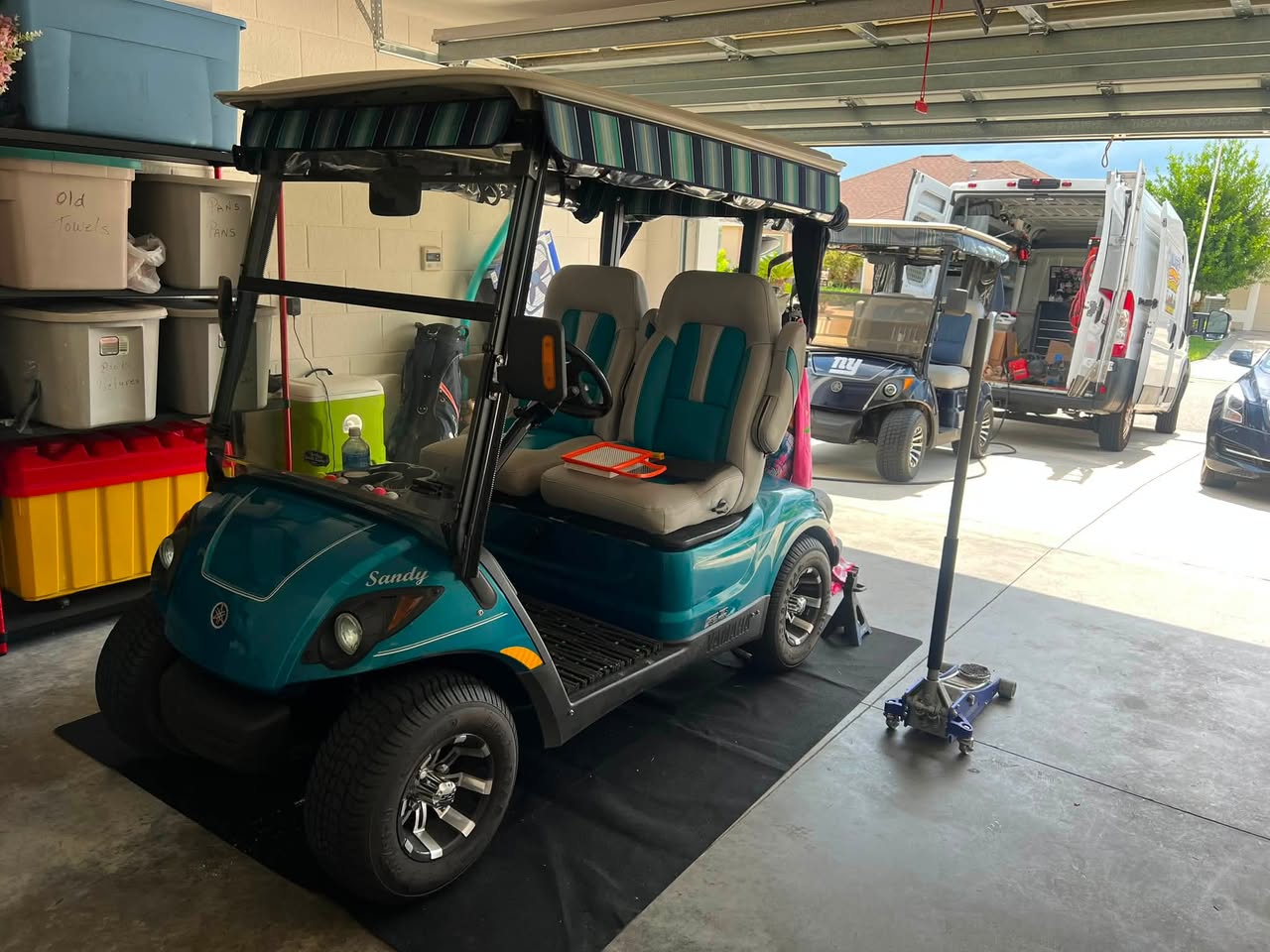 Teal Yamaha golf cart on a jack in a garage during a mobile repair visit