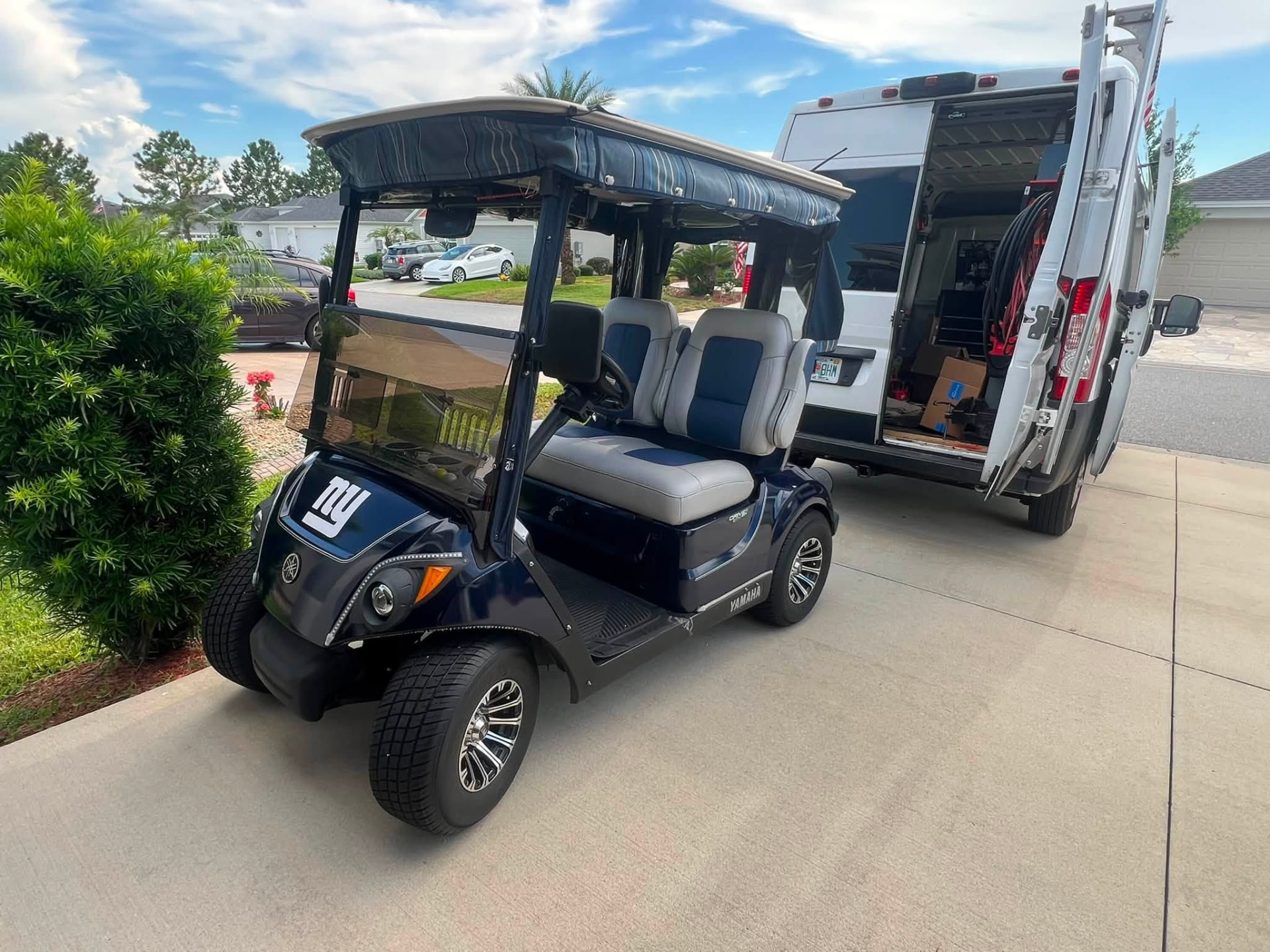Navy golf cart parked beside the Village Mobile Mechanic service van