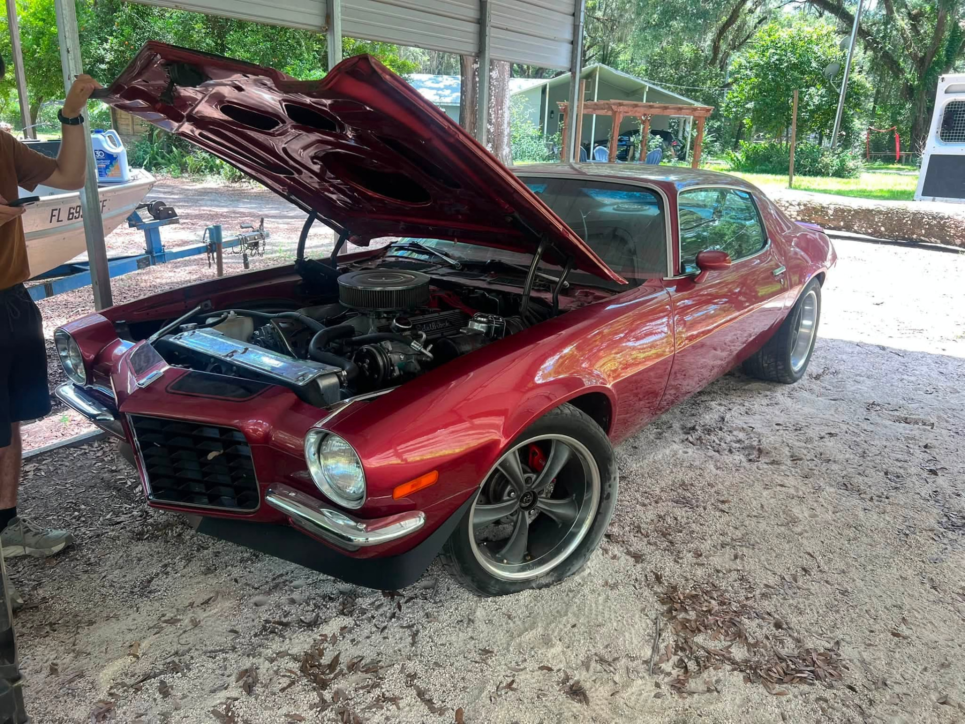 Classic red Camaro with the hood up during an on-site repair