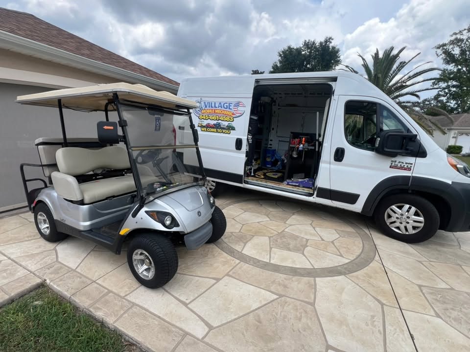 Silver golf cart parked in a driveway next to the open mobile mechanic van